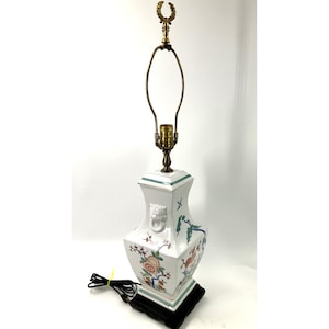 May include: A set of three ceramic mugs with a speckled, cream-colored glaze. Each mug features a different hand-painted design: a blue and green leaf, a yellow and orange flower, and a red and pink berry. The mugs have a simple, rounded shape.