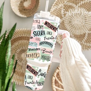 May include: A white tumbler with a green and pink design featuring Spanish words like "inteligente", "fuerte", and "unica".