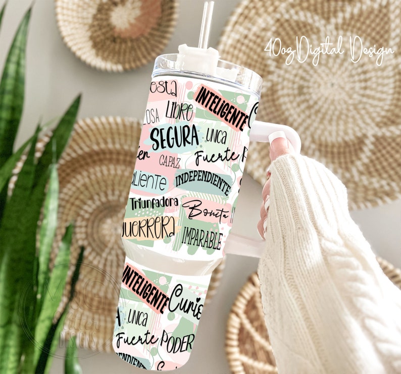 May include: A white tumbler with a green and pink design featuring Spanish words like "inteligente", "fuerte", and "unica".