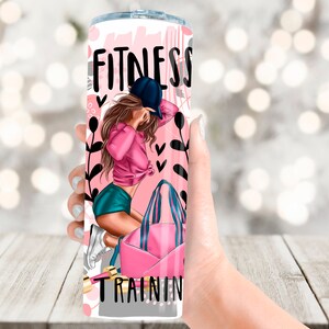 May include: A pink and white tumbler with a graphic of a woman in a pink shirt and blue shorts holding a pink gym bag. The tumbler has the text "Fitness Training" on it.