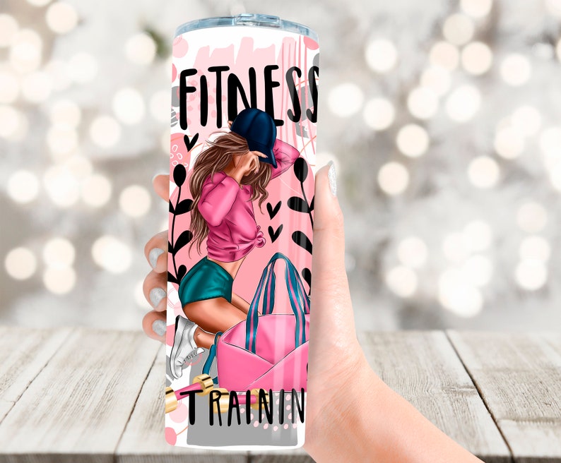 May include: A pink and white tumbler with a graphic of a woman in a pink shirt and blue shorts holding a pink gym bag. The tumbler has the text "Fitness Training" on it.
