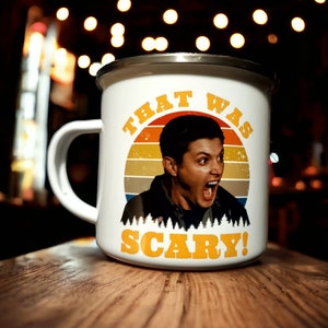 May include: White enamel mug with a retro sunset graphic and a man's face. The text "That Was Scary!" is printed in yellow on the mug.