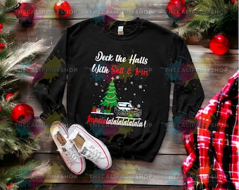 Könnte beinhalten: Schwarzes Langarmshirt mit einem Weihnachtsbaum- und einem Automotiv. Der Text "Deck the Halls with Salt & Iron" und "Impalalalalalalalala!" ist auf dem Sweatshirt aufgedruckt.