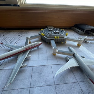 May include: A model airport terminal with three airplanes, one with the text "malaysia" on the side, another with the text "airbus" on the side, and a third with the text "ANA" on the side.