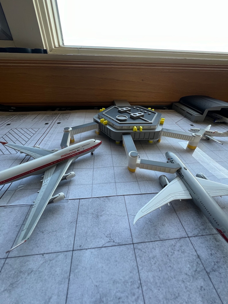 May include: A model airport terminal with three airplanes, one with the text "malaysia" on the side, another with the text "airbus" on the side, and a third with the text "ANA" on the side.