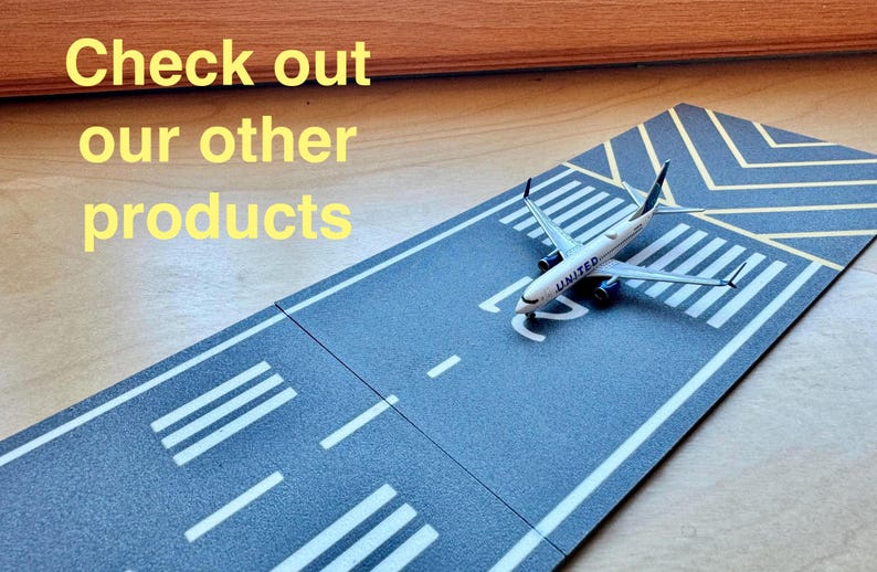 May include: A toy airplane model of a United Airlines plane on a gray and white runway playset. The runway has white lines and yellow markings.