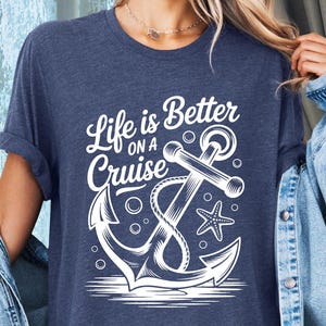 May include: Heather navy blue t-shirt with the text "Life is Better on a Cruise" and a white anchor design. The design includes an anchor, starfish, and bubbles. The shirt is a comfortable, casual style.