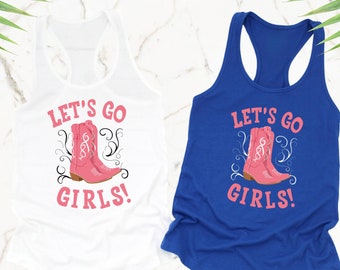 Puede incluir: Dos camisetas sin mangas con el texto "Let's Go Girls!" y un par de botas vaqueras rosas. Una camiseta sin mangas es blanca y la otra es azul.