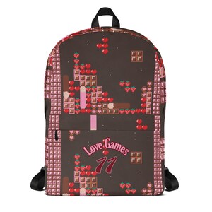 Könnte beinhalten: Ein brauner Rucksack mit einem Pixel-Design mit Erdbeeren, Schokoladentafeln und Herzen. Der Rucksack hat einen pinkfarbenen und braunen Gurt und den Text "Love Games 77" in Pink und Rot.