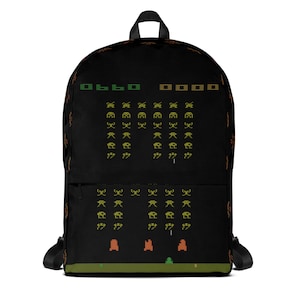 May include: Black backpack featuring a pixelated graphic of a classic arcade game. The design includes green and orange pixelated aliens and the text "0660 00000" at the top. The backpack has black shoulder straps and a top handle.