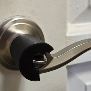 May include: A silver door handle with a black rubber safety cover installed on the handle.