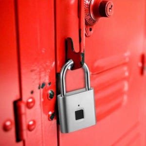 Peut inclure: Un cadenas biométrique argenté avec un corps rectangulaire et une anse en forme de U, doté d'un petit capteur d'empreintes digitales noir sur la face avant, fixé au loquet d'une porte de casier en métal rouge vif avec un verrou à cadran.