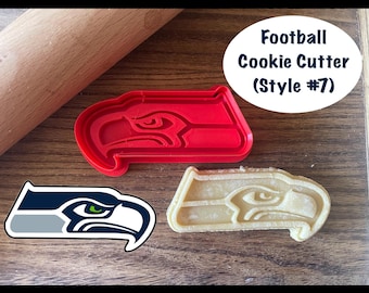 Könnte beinhalten: Ein roter Fußball-Ausstecher aus Kunststoff in Form eines Vogelkopfes, neben einem Keks, der in derselben Form geschnitten wurde. Ein Logo des Vogelkopfes ist ebenfalls abgebildet. Der Text lautet "Football Cookie Cutter (Style #7)".