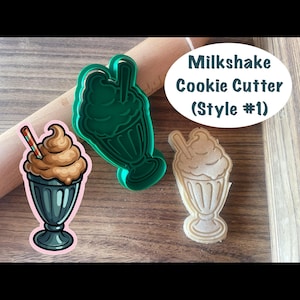 May include: A green plastic milkshake cookie cutter, a tan dough cutout of a milkshake, and a colorful illustration of a milkshake with a straw. The text Milkshake Cookie Cutter (Style #1) is printed on a white oval background above the items.