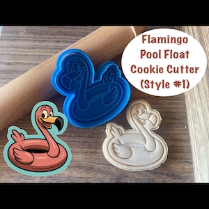 Puede incluir: Un cortador de galletas de flamenco flotante (Estilo #1) de plástico azul junto a una galleta de flamenco y un rodillo. La galleta es rosa y el texto dice "Flamingo Pool Float Cookie Cutter (Style #1)".