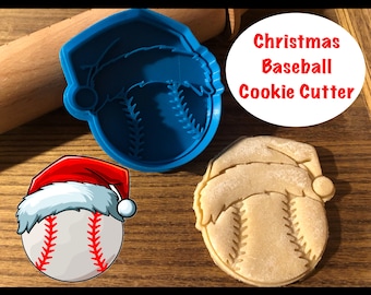 May include: Blue plastic Christmas baseball cookie cutter with a Santa hat on top. The cutter is shown next to a cookie that has been cut out using the cutter.