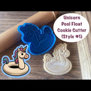 May include: A blue plastic unicorn pool float cookie cutter next to a cookie and a sticker of a unicorn pool float. The sticker and cookie cutter are in the shape of a unicorn floating on an inner tube. The text on the image says "Unicorn Pool Float Cookie Cutter (Style #1)".