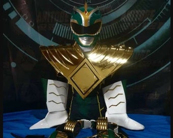 May include: Green Power Ranger costume with a gold chest piece, white gloves, and a white helmet with a green visor. The costume also includes a belt with a gold buckle and a green Power Ranger logo.