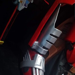 May include: Red and silver costume boot with a silver strap and a silver shin guard with three slits.