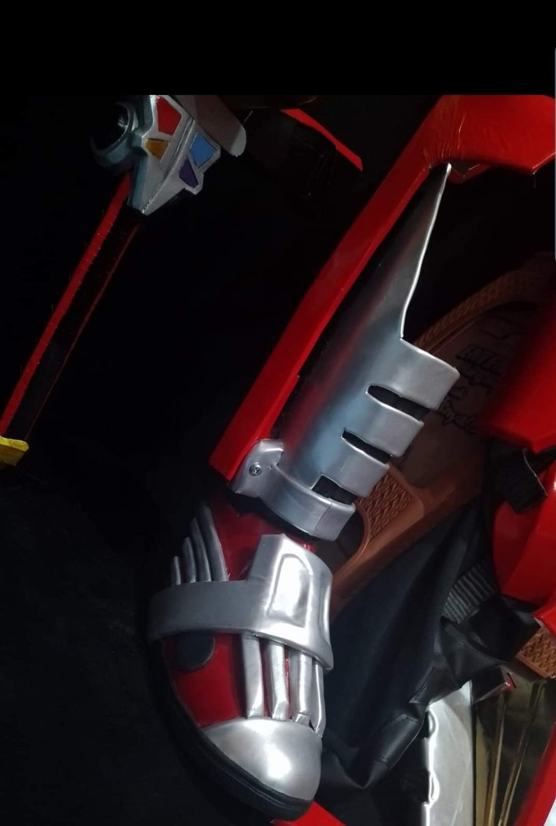 May include: Red and silver costume boot with a silver strap and a silver shin guard with three slits.