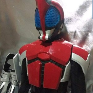 May include: A red and black costume with a helmet featuring a blue visor and a red antenna. The costume has a silver chest plate with a black and red design.