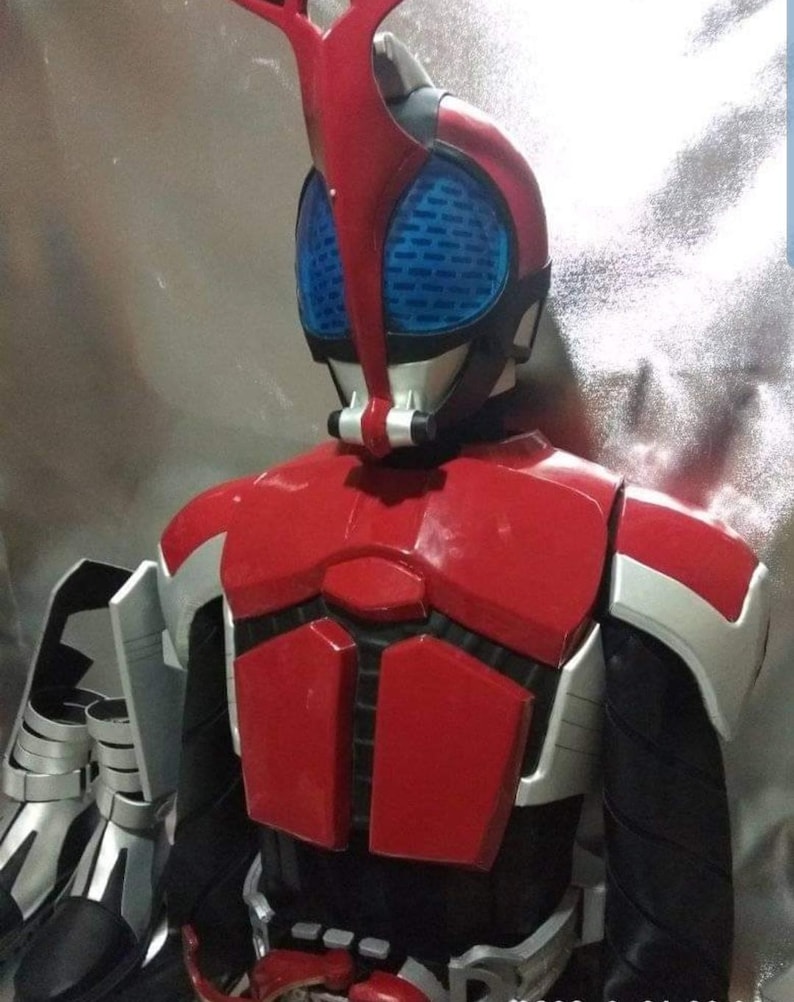 May include: A red and black costume with a helmet featuring a blue visor and a red antenna. The costume has a silver chest plate with a black and red design.
