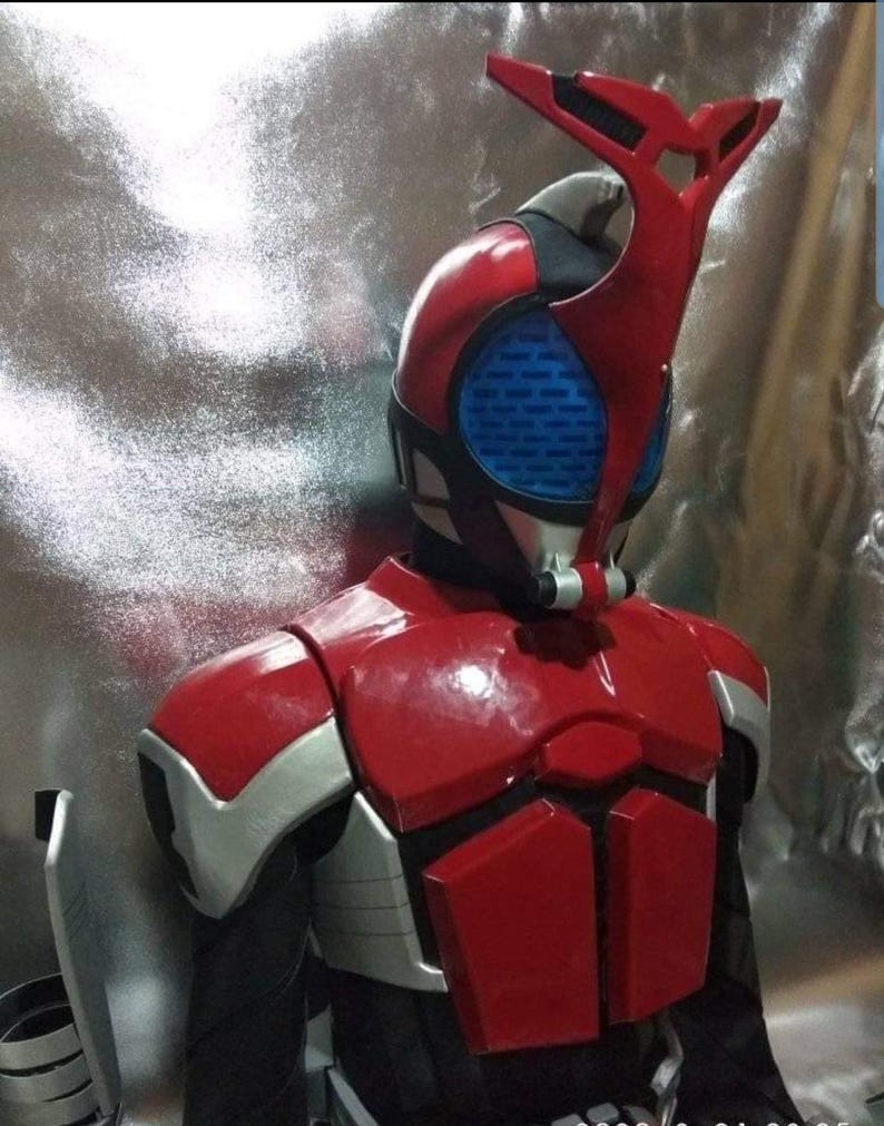 May include: A red and silver costume with a helmet featuring a blue visor and a red and black antenna. The costume is a popular character from a Japanese television show.