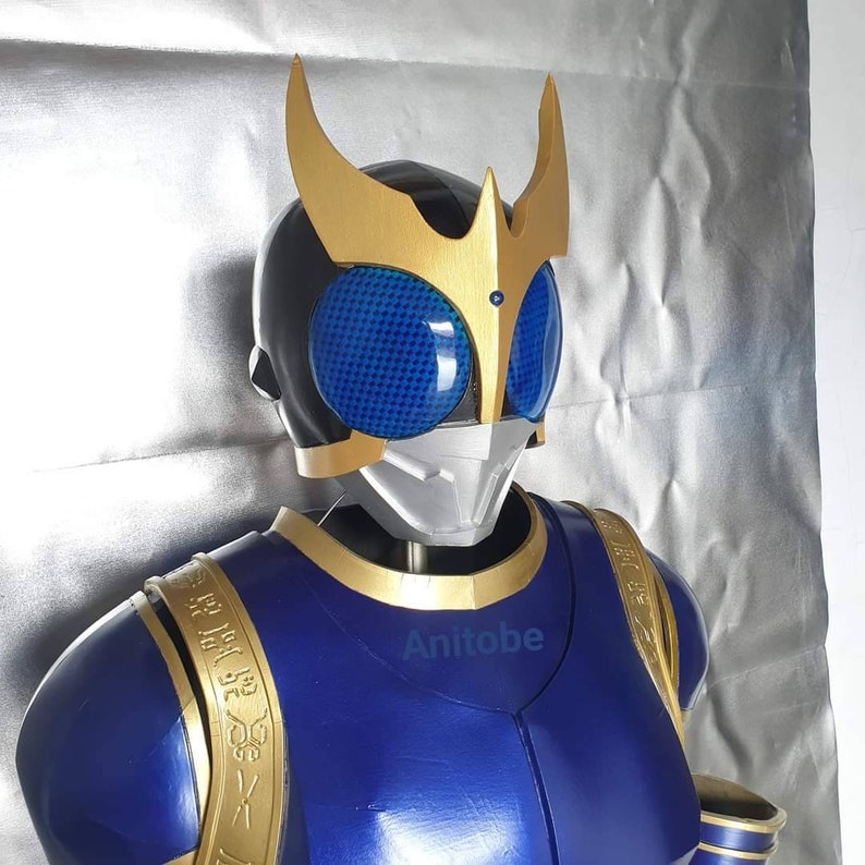K&ouml;nnte beinhalten: Ein blaues und goldenes Kost&uuml;m mit einem schwarzen Helm mit blauen und silbernen Akzenten. Der Helm hat eine goldene Krone mit zwei Spitzen. Das Kost&uuml;m hat goldene Akzente an den Schultern und der Brust.