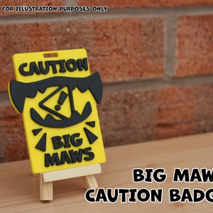 Puede incluir: Un cartel de precaución amarillo y negro con el texto "CAUTION" y "BIG MAWS" impreso en él. El cartel está sobre un pequeño caballete de madera. El cartel es una advertencia sobre una boca grande.