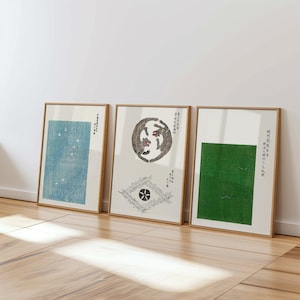 Puede incluir: Tres impresiones enmarcadas con obras de arte de estilo japonés. La impresión de la izquierda presenta un fondo azul con puntos blancos. La impresión del centro presenta una ilustración en blanco y negro de dos animales en un círculo. La impresión de la derecha presenta un fondo verde con puntos blancos.
