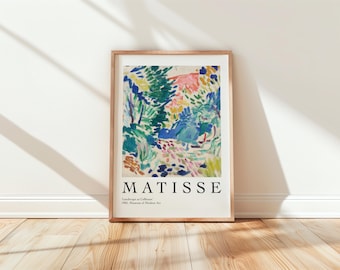 May include: A framed print of a colorful abstract painting by Henri Matisse titled "Landscape at Collioure". The painting features a vibrant mix of blue, green, yellow, pink, and white brushstrokes, depicting a landscape with trees and foliage. The print includes the artist's name "MATISSE" and the title of the painting in black text below the image.
