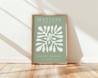 May include: A framed print with a green background and a white abstract floral design. The print features the text "MATISSE" and "GALERIE MAEGHT" in white.