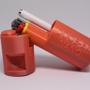May include: A red plastic case with the words "DOOB-EZ NANO" printed on the side. The case is open and contains a lighter and a small white tube.