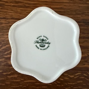 May include: A white bone china dish with a scalloped, flower-like edge. The center features a green stamp that reads BONE CHINA, Hammersley, and MADE IN ENGLAND, with an acorn and crown icon positioned above and below the brand name.