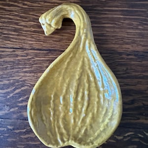 May include: A yellow ceramic dish shaped like a gourd with a textured surface. The dish is perfect for serving snacks or holding small items.