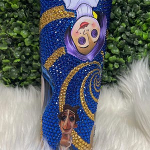 May include: A blue and gold tumbler with a swirling pattern and images of characters from the film "The Nightmare Before Christmas".