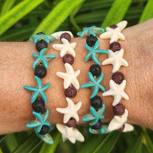 May include: Four stretch bracelets featuring alternating beads. Two bracelets consist of turquoise starfish charms and black porous lava beads. Two bracelets feature off-white starfish charms and dark brown spherical beads.