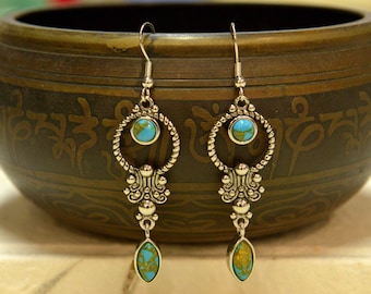 May include: A pair of silver dangle earrings with turquoise stones. The earrings feature a circular design with a smaller turquoise stone at the bottom.