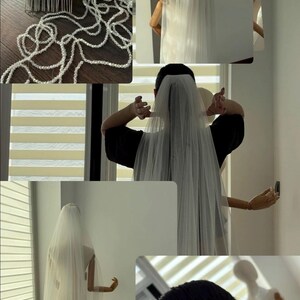 May include: A white bridal veil with a comb and beaded accents. The veil is long and flowing, and is shown on a mannequin and being worn. The veil is made of a sheer, lightweight fabric.