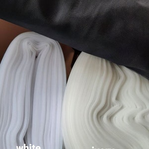 May include: Close-up of three fabric swatches: black, white and ivory. The fabric is a fine mesh.