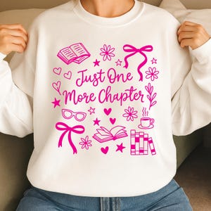 Può includere: Felpa bianca con grafica rosa che recita "Just One More Chapter". Il design include libri, cuori, stelle, fiori, occhiali e fiocchi. Un capo comodo per gli amanti della lettura.