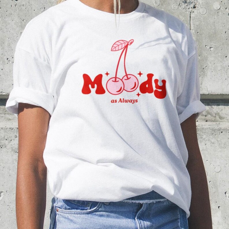 May include: White t-shirt with a red graphic of two cherries and the text "Moody as Always".