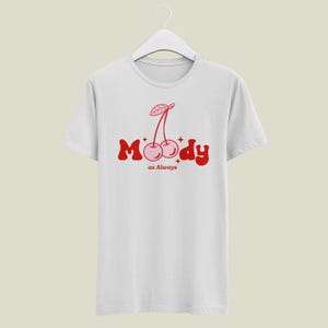 May include: White t-shirt with a red graphic of two cherries and the text "Moody as Always".