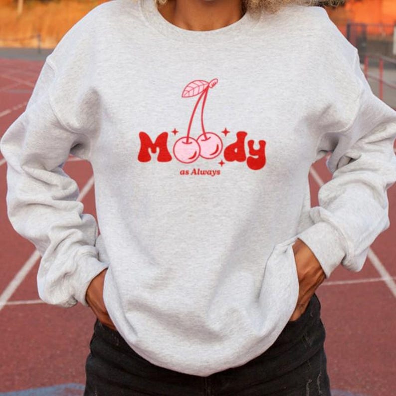 May include: A gray sweatshirt with a red and pink cherry graphic and the text "Moody as Always".
