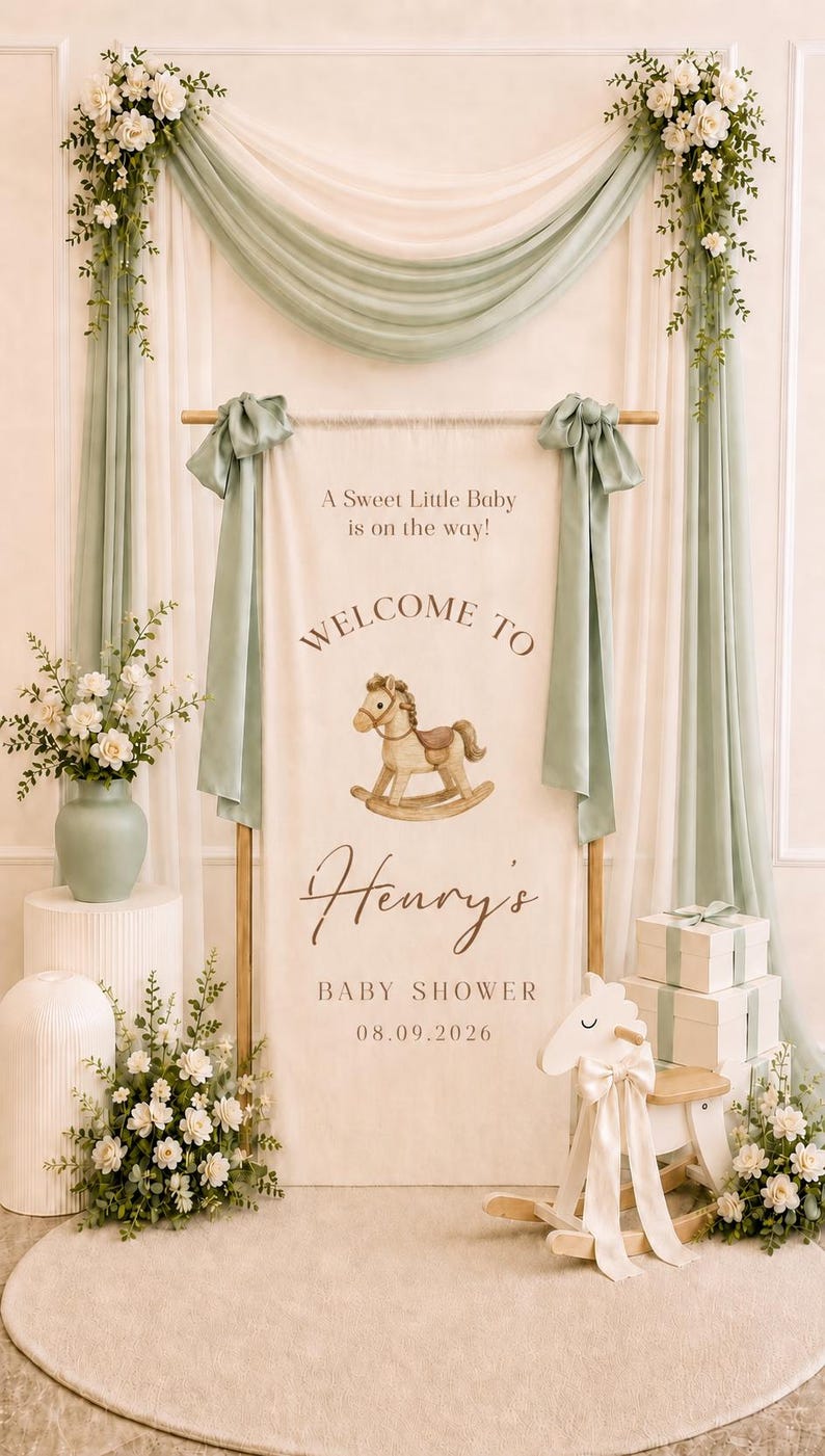 May include: A vertical fabric banner featuring the text A Sweet Little Baby is on the way! WELCOME TO Henry's BABY SHOWER 08.09.2026 with a watercolor rocking horse illustration, suspended from a wooden rod with sage green fabric drapes.