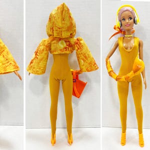 K&ouml;nnte beinhalten: Eine Puppe mit hellviolettem Haar tr&auml;gt einen senfgelben Body, passende spitze Abs&auml;tze und eine Kapuzenjacke mit gelb-orangem Batikmuster. Zu den Accessoires geh&ouml;ren eine violette Sonnenbrille, gelbe Kopfh&ouml;rer und eine kleine orangefarbene Handtasche.