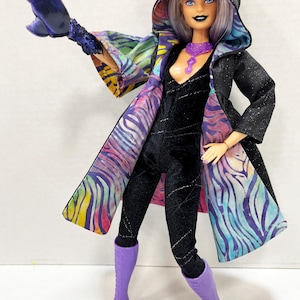 May include: A fashion doll in a black jumpsuit and a hooded coat with a colorful zebra print lining. The doll has purple boots, a purple necklace, and a matching arm accessory. The doll's hair is light purple, and it has dark makeup.