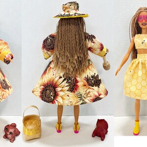 Puede incluir: Mu&ntilde;eca con un atuendo amarillo con abrigo, sombrero y falda con estampado de girasoles. La mu&ntilde;eca lleva gafas de sol rosas y botas amarillas. Accesorios: cesta, cuchara de miel y figurita de oso.