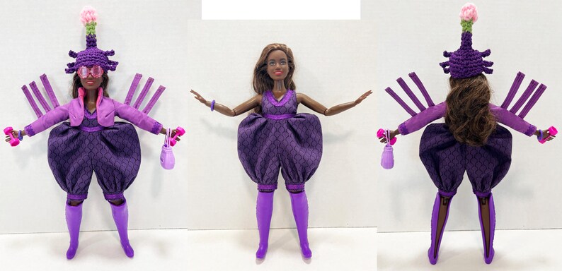 May include: A fashion doll in a purple outfit with a matching hat and accessories. The doll is wearing a purple jacket, a dress with a unique pattern, and purple boots. The doll is holding a small purse and weights. The hat has a pink flower.