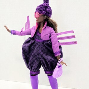 May include: A fashion doll in a purple outfit, including a jacket, romper, and boots. The doll wears a unique hat with a pink and green top, pink sunglasses, and carries a matching purse. The romper has a patterned design.